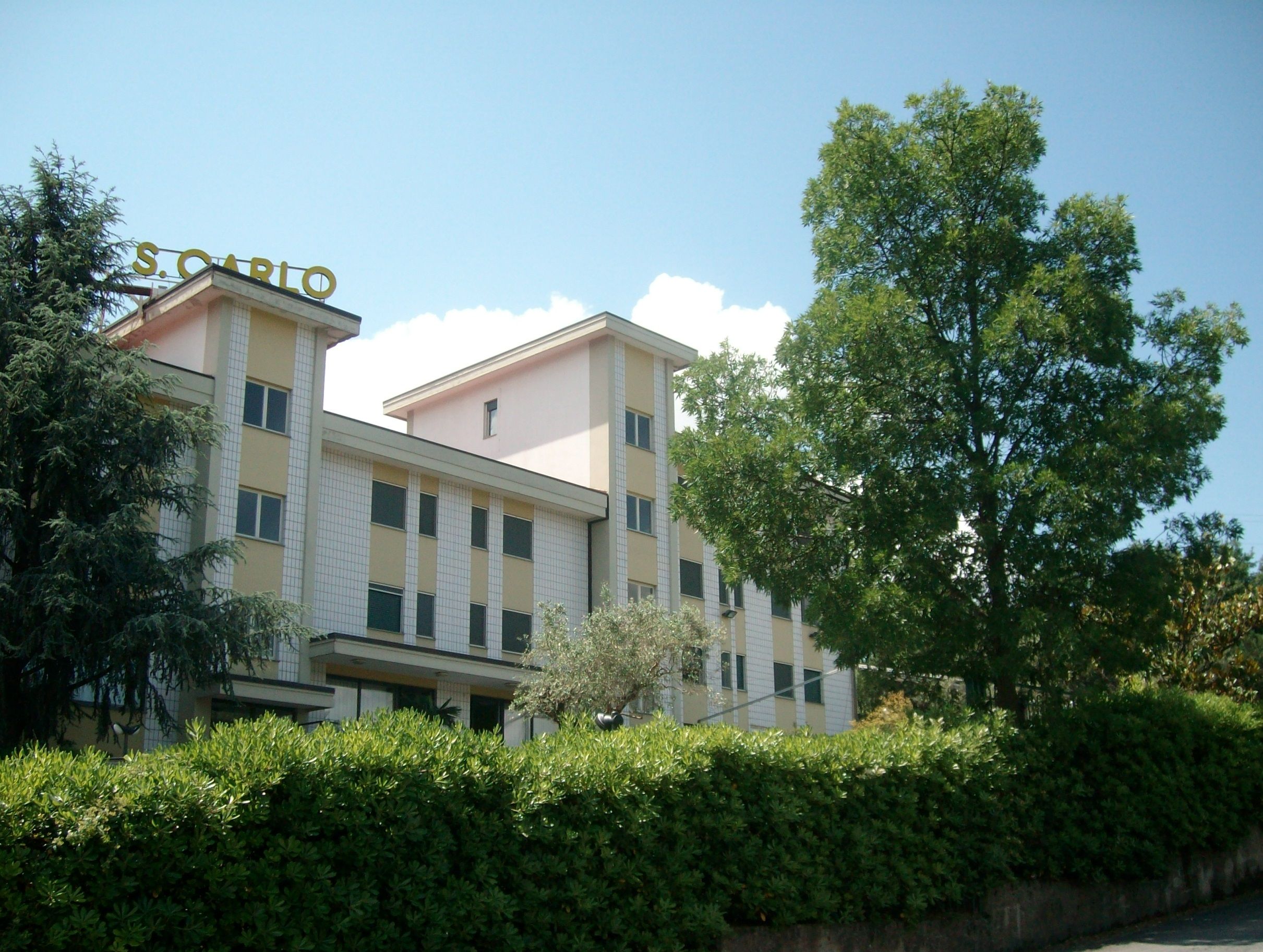 La facciata di Villa San Carlo con l’insegna, tra gli alberi