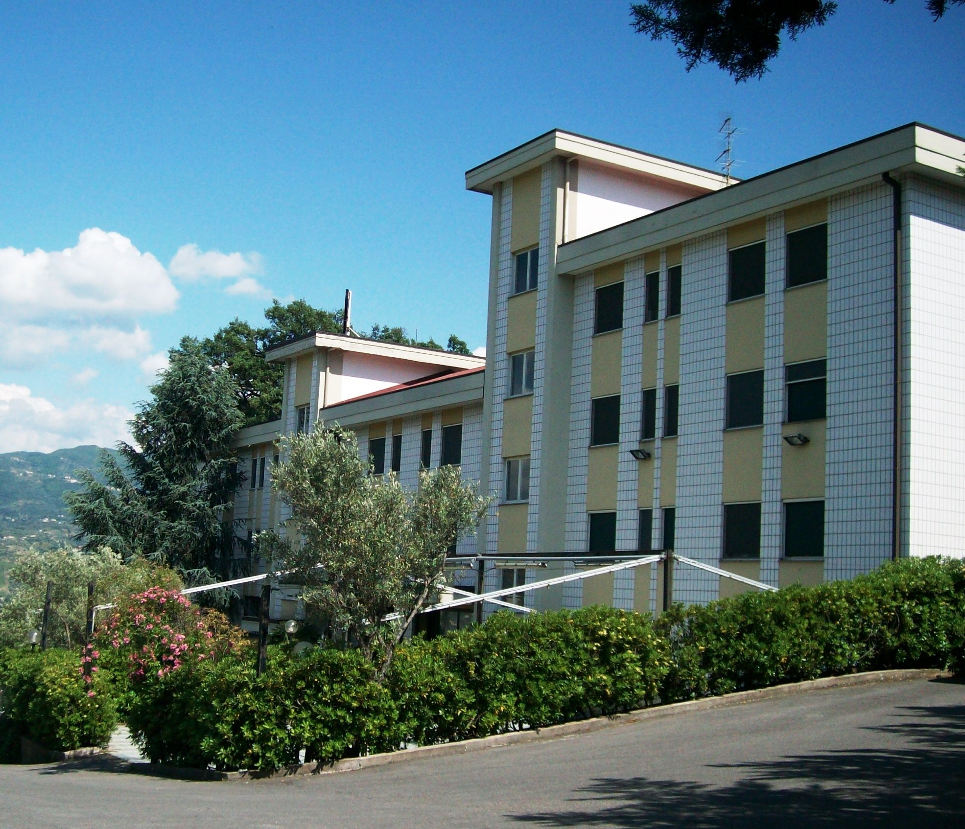 Vista esterna dell’edificio con siepi e cielo azzurro